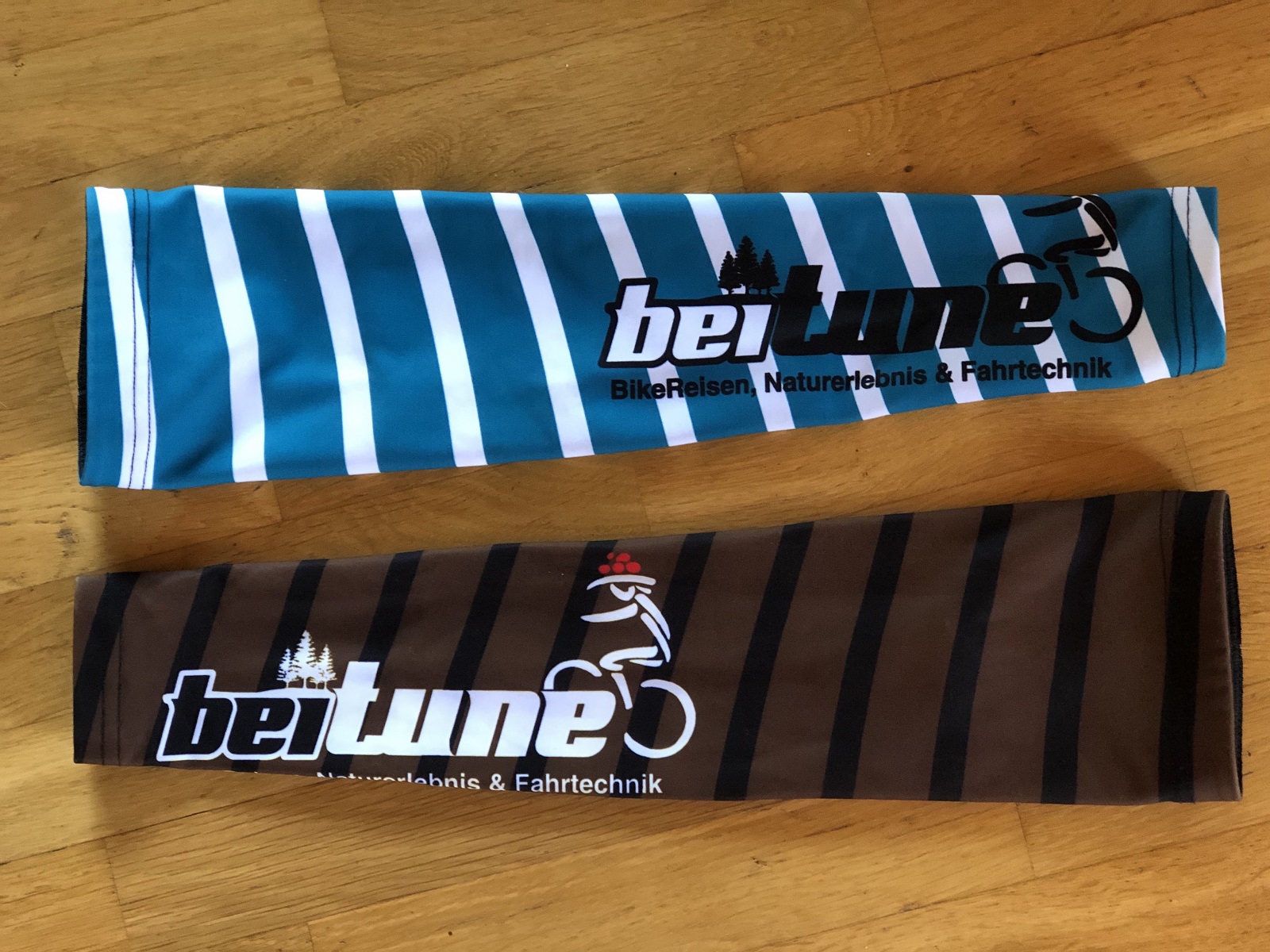 beitune Armlinge in braun und türkis mit Streifen und beitune Logo.